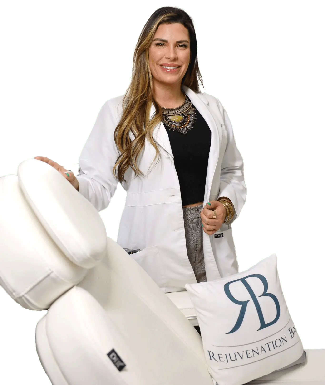 Smiling woman in a white lab coat standing beside a white treatment chair with a Rejuvenation Bar logo pillow